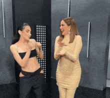 two women are standing next to each other in a dark room