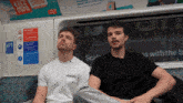 two men are sitting on a train with a sign that says sale on it