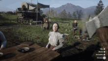 a woman sits at a table in a video game while a man sits on a bench in the background
