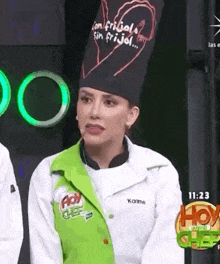 a woman wearing a chef 's hat and a green vest is talking on a radio show .