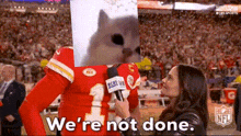 a man in a chiefs jersey is being interviewed by a woman with a dog on his head .