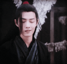 a close up of a man with his eyes closed wearing a black robe