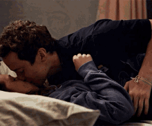 a man in a black shirt kisses a woman in a gray sweatshirt