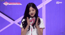 a girl in a school uniform is clapping her hands on a stage .