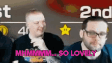 two men are sitting in front of a sign that says " 2nd "
