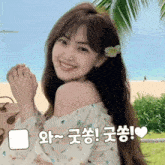 a woman with a flower in her hair is smiling in front of a palm tree