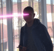 a man is standing in front of a window with a purple light coming out of his eyes