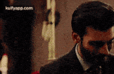 a man with a beard wearing a suit and tie is looking at the camera .
