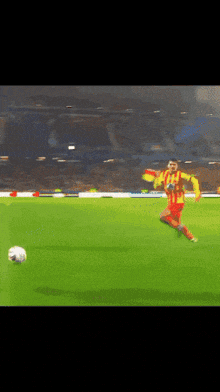 a soccer player in a yellow and red uniform kicking a soccer ball