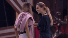 two women standing next to each other with one wearing a pink sweater