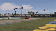 a red car driving down a race track with a crane in the background