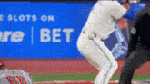 a baseball player in front of a sign that says " slots on bet "
