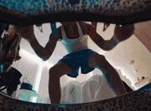 a man in a white tank top and blue shorts stands in front of a leopard print wall