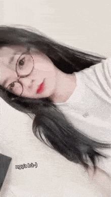 the girl is wearing glasses and a white shirt and taking a selfie .