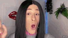 a woman wearing a wig and a striped shirt is making a funny face ..