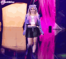 a woman in a denim jacket and black skirt walks down a stage with the words livin ' bliss on the bottom