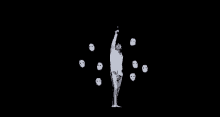 a man in a white shirt is standing in front of a bunch of white masks on a black background .