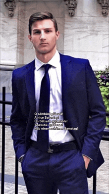 a man in a suit and tie is standing in front of a fence with his hands in his pockets