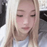a close up of a woman 's face with blonde hair and pink blush .