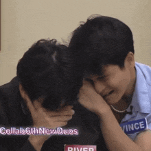 a couple of men are sitting next to each other and one of them is covering his face with his hand