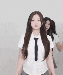 a girl in a school uniform and tie is standing with her arms outstretched and looking at the camera .