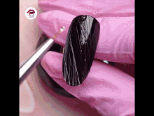 a pink glove is holding a black nail with a spider web design