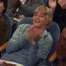 a man in a blue shirt is clapping in a crowd of people