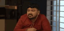 a man with a beard is wearing a red shirt and headphones .
