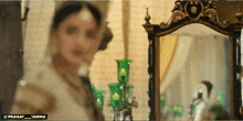a woman stands in front of a mirror with the name pranay written on the bottom