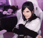 a woman in a baseball cap is sitting in a chair with her arms around her shoulders .