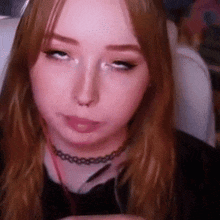 a close up of a woman wearing a choker making a funny face while sitting in a chair .