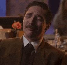 a man in a suit and tie covering his face with his hands .
