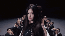 a woman with long hair is standing in front of a crowd of people
