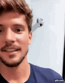 a close up of a man 's face with a beard and a blue shirt .