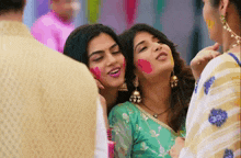 two women are standing next to each other with their faces painted with holi colors