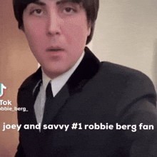 a man in a suit and tie with the words joey and savvy # 1 robbie berg fan