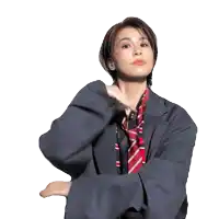 a woman in a suit and tie has her arm up