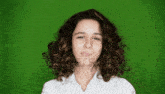 a young girl with curly hair is making a funny face against a green screen .