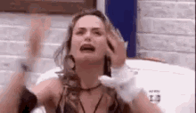 a woman is crying and holding her head while sitting on a bed .