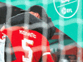 a man wearing a red jersey with the number 5 on it is hugging another man