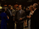 a man in a suit is talking to a woman in a white dress