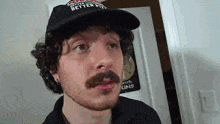 a man with a beard and mustache is wearing a hat and looking at the camera .