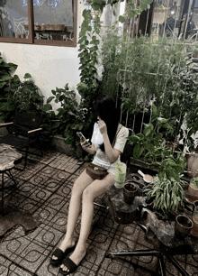 a girl is sitting on a brick floor looking at her phone