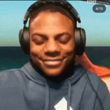 a man wearing headphones and a blue hoodie is smiling with the number 4/10 in the corner