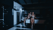 a group of women standing in a kitchen with one wearing a crop top that says ' i love you ' on it