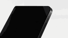 a close up of a black cell phone on a white surface