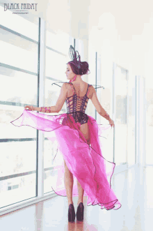 a woman in a pink dress is standing in front of a window with black friday written on the bottom of the photo