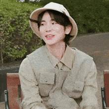 a young man wearing a hat and a vest is sitting on a bench