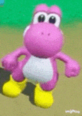 a pink yoshi toy with yellow boots is standing on a dirt field .