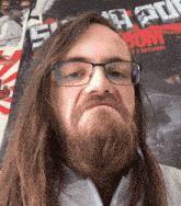 a man with glasses and a beard stands in front of a poster that says ' e3 novembre ' on it
